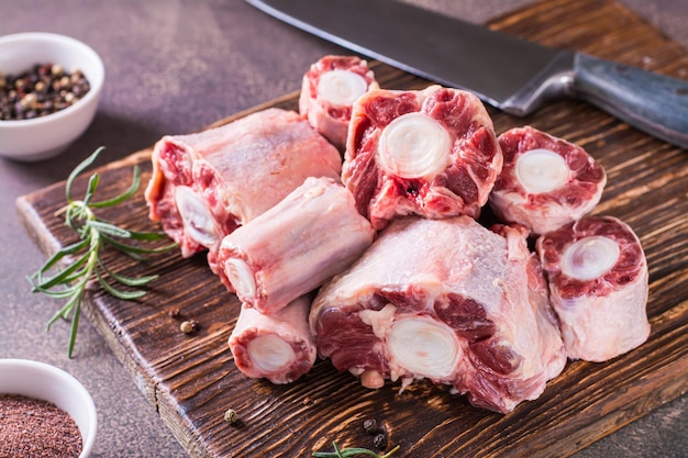 Pieces of raw oxtail and spices for cooking on a wooden board on the table