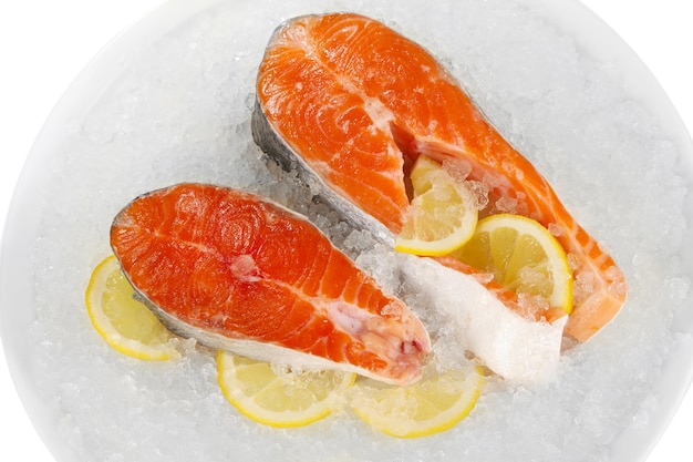 Pieces of red fish on ice in plate isolated on white