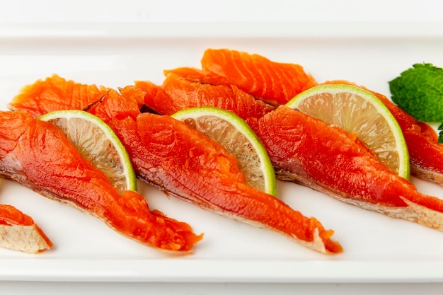 Pieces of red fish with lime on a white plate Delicious and healthy snack Closeup