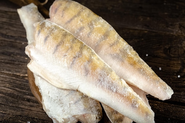 pieces of red and white fish fillet in a package frozen in a cardboard plastic, open, on a dark wood