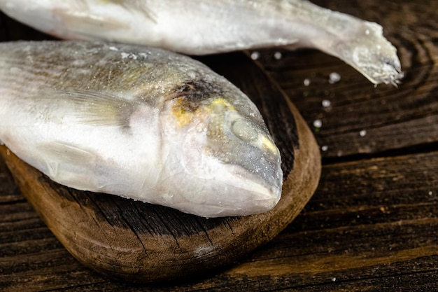 赤と白の魚の切り身の小片は、段ボールのプラスチックで冷凍されたパッケージに入れられ、開いた状態で、ダークウッドの上に置かれます