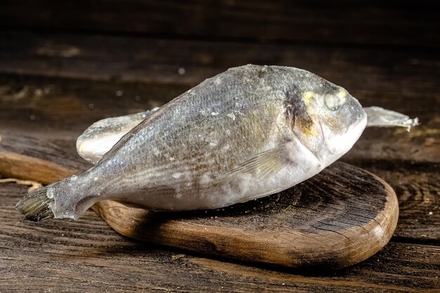 pieces of red and white fish fillet in a package frozen in a cardboard plastic, open, on a dark wood