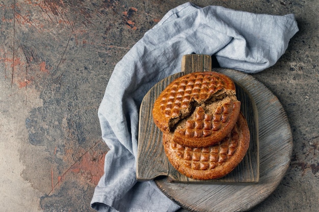 Pieces of rye flatbread lie on a wooden board and a cotton napkin copy space