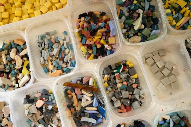 Pieces of smalt for mosaic in plastic containers. Small Colored stones for creativity, mosaic panels