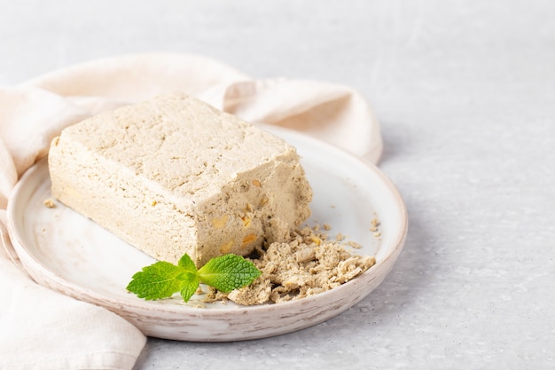 pieces of sunflower halva with peanuts in a gray plate mint light gray background