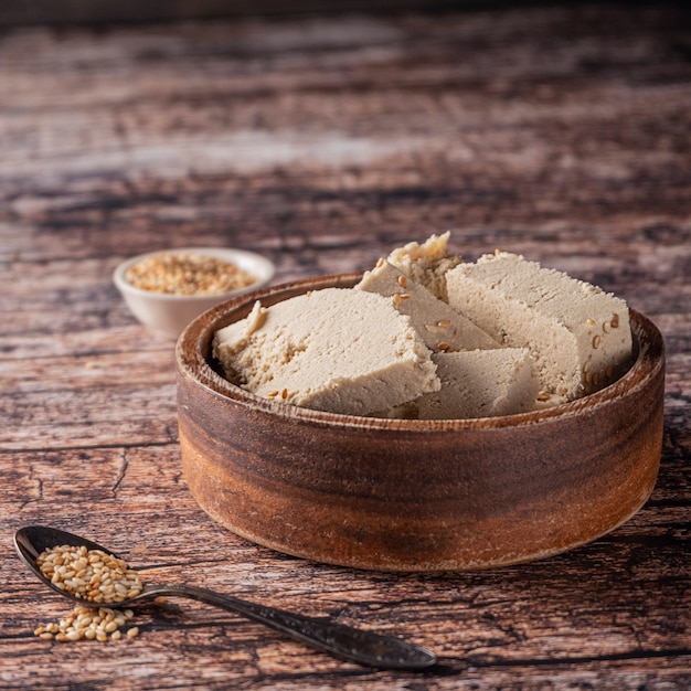 Pieces of tahini halva in a bowl on vintage wooden table