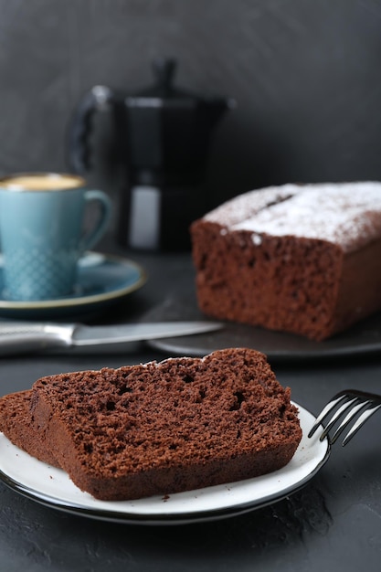 Pieces of tasty chocolate sponge cake on black table Space for text