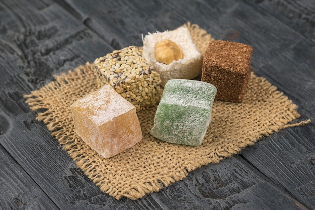 Pieces of Turkish delight on a piece of burlap on a wooden table. Oriental sweets.