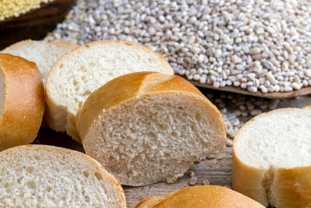 Pieces of wheat baguette on a cutting board pieces of wheat baguette with raw dry cereals and barley