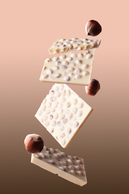 Photo pieces of white chocolate with nuts on a beige background flying food