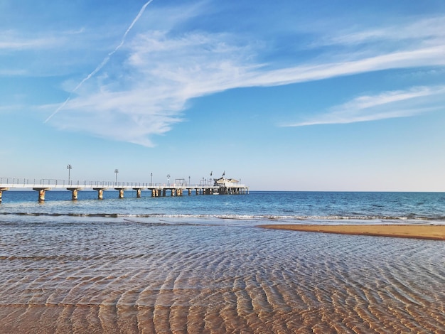 Pier on beach against sky