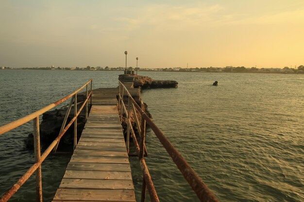 Photo a pier extending towards the gulf of aden at sunset time