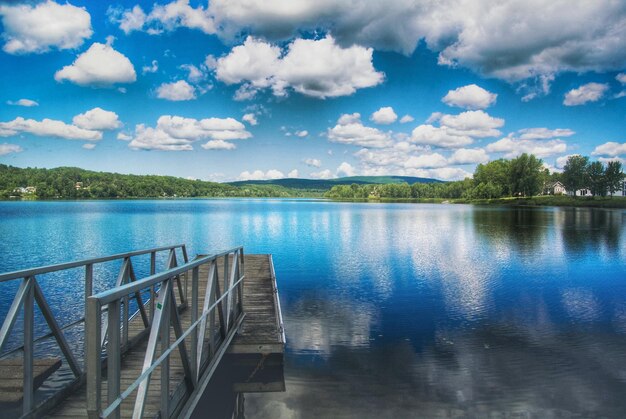 Photo pier over lake against cloudy sky