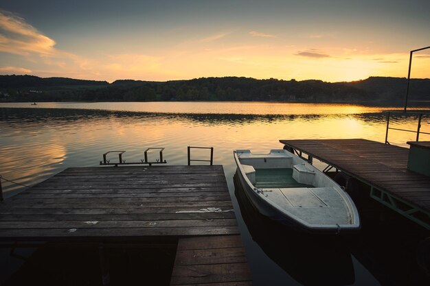 Pier over lake against sky during sunset