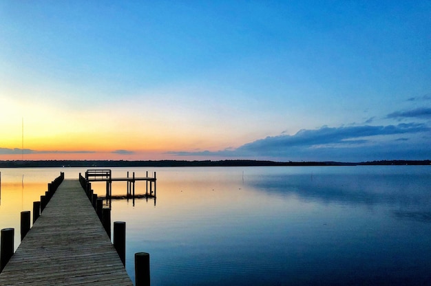 Photo pier over lake against sky during sunset