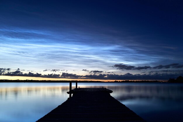 Pier over lake against sky during sunset