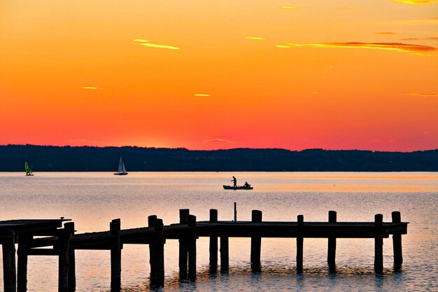 Pier over lake against sky during sunset