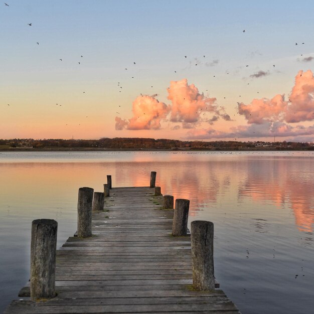 Photo pier on lake against sky during sunset