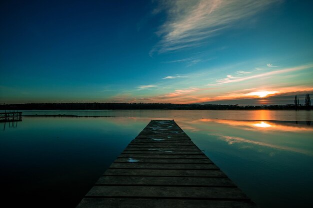 Photo pier over lake against sky during sunset