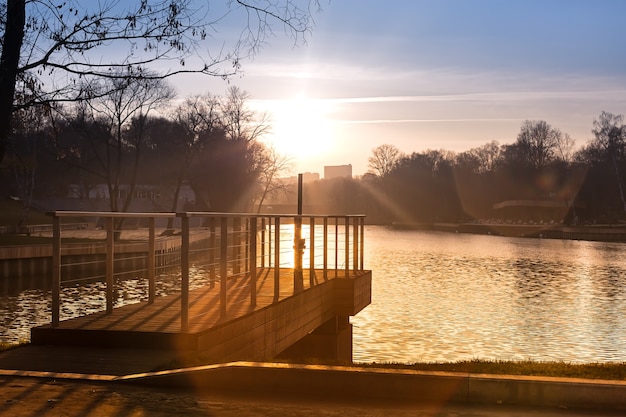 Pier op het meer in het stadspark Herfstzonsondergang een prachtig zonnepad op het water