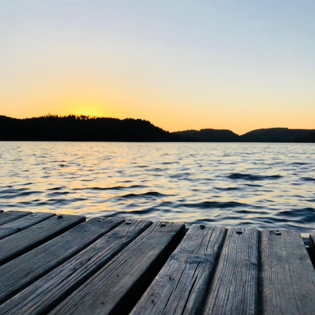 Pier over het meer tegen een heldere hemel tijdens de zonsondergang