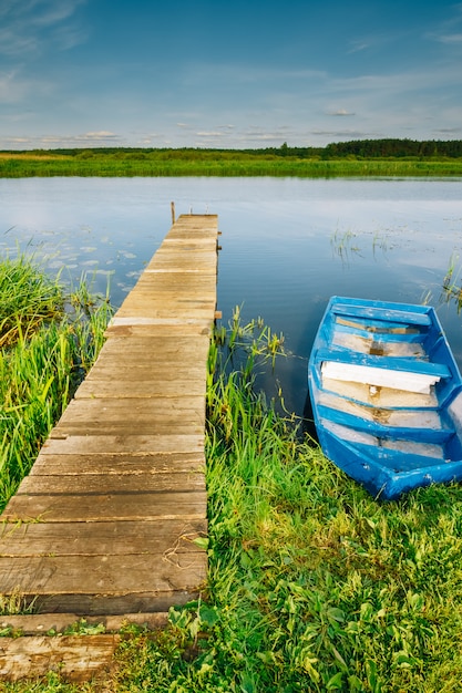 The pier on the river and the boat at the shore. Summer