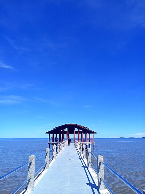 Pier over sea against blue sky