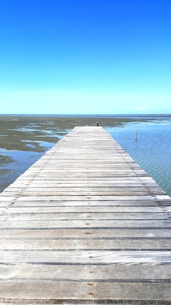 Pier over sea against clear blue sky