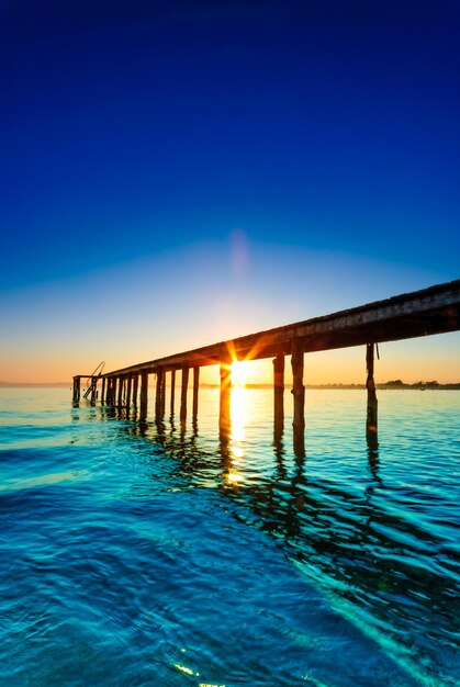 Pier over sea against clear blue sky