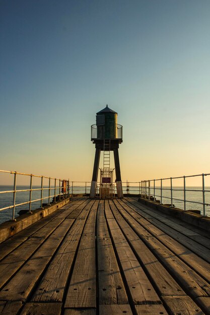 Photo pier over sea against clear sky during sunset