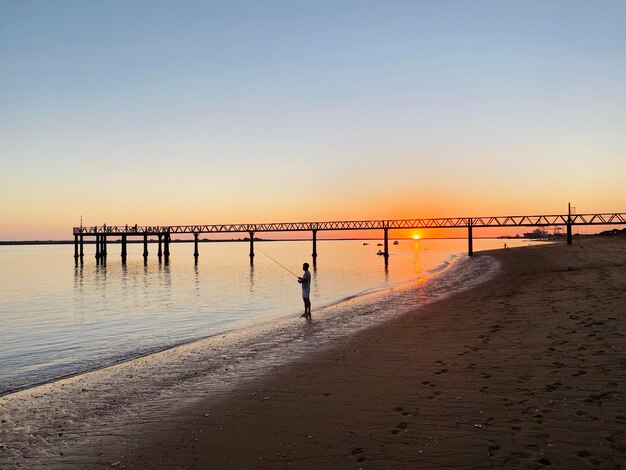 Pier over sea against clear sky during sunset