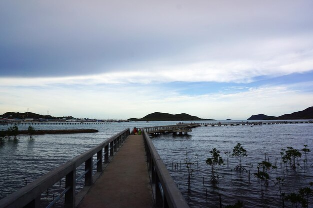 Pier on sea against cloudy sky