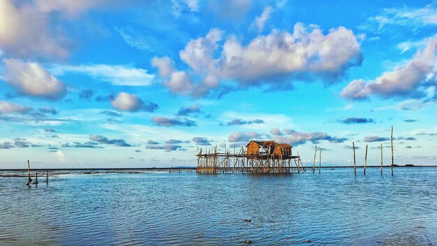 Pier on sea against cloudy sky