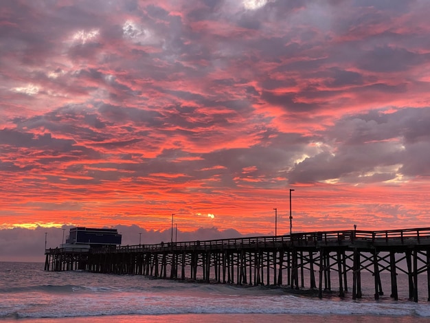 Photo pier over sea against dramatic sky during sunset