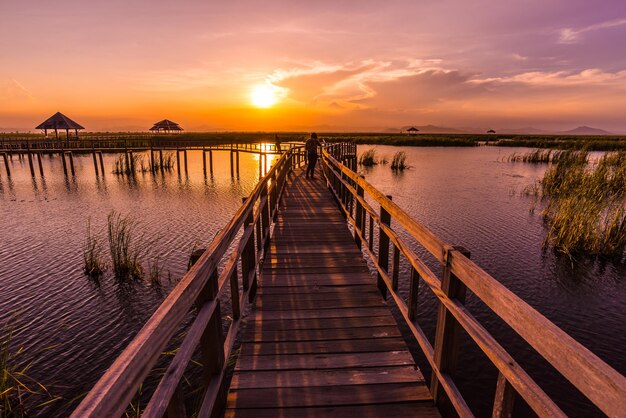 Pier over sea against orange sky