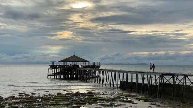 Pier over sea against sky during sunset