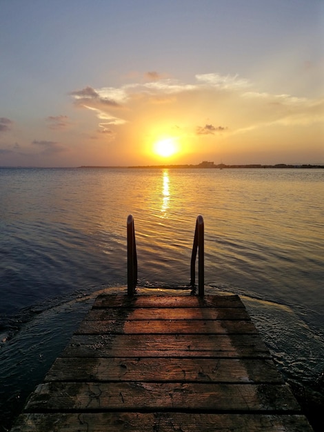 Pier over sea against sky during sunset