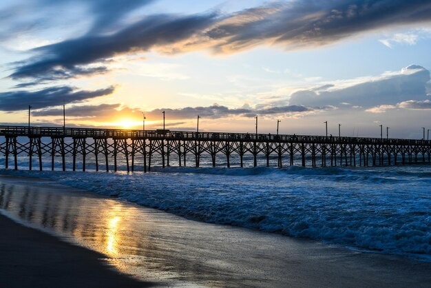 Pier over sea against sky during sunset