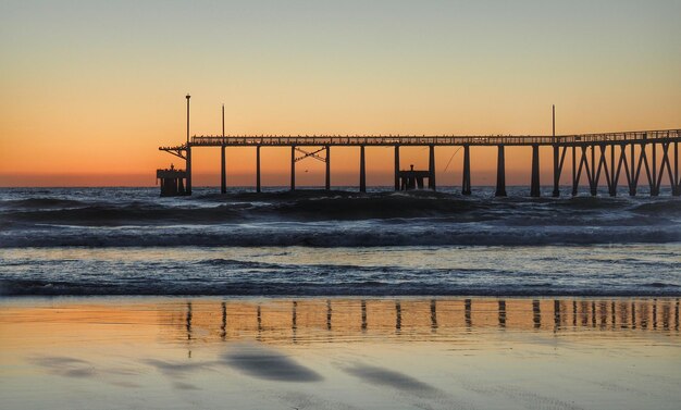 Pier on sea against sky during sunset