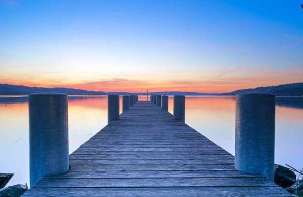 Pier over sea against sky during sunset