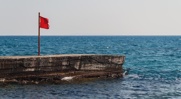 Pier with a red flag in the sea