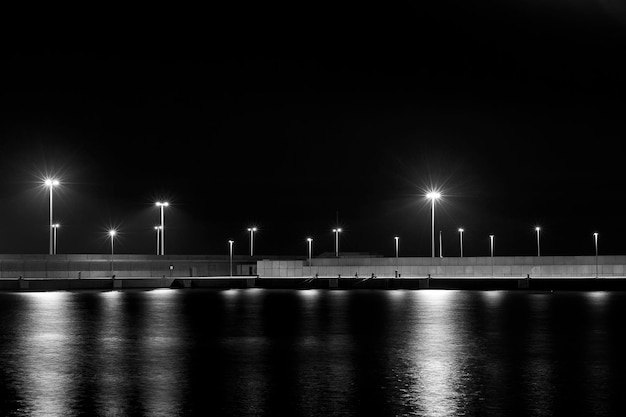 A pier with several street lights and a body of water.