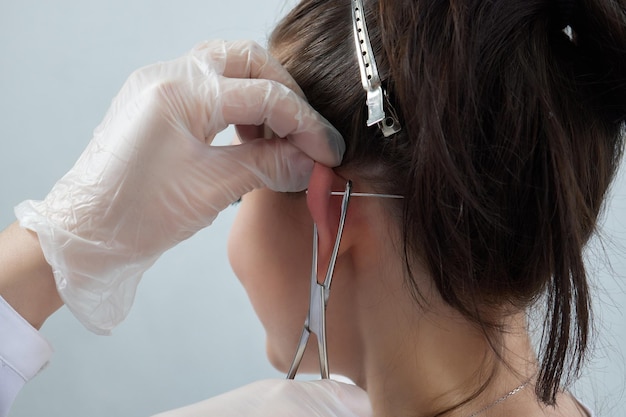 Piercings on an ear conch and helix piercings close up professional holding the jewel