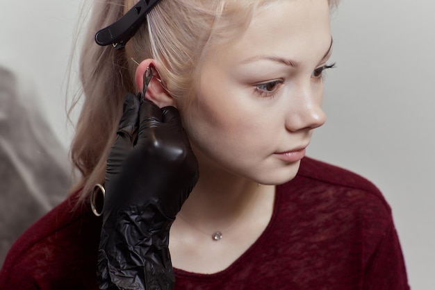 Piercings on an ear Conch and helix piercings close up Professional holding the jewel