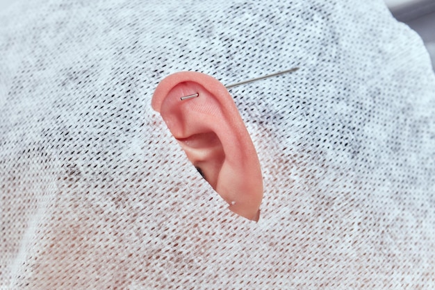 Piercings on an ear Conch and helix piercings close up Professional holding the jewel