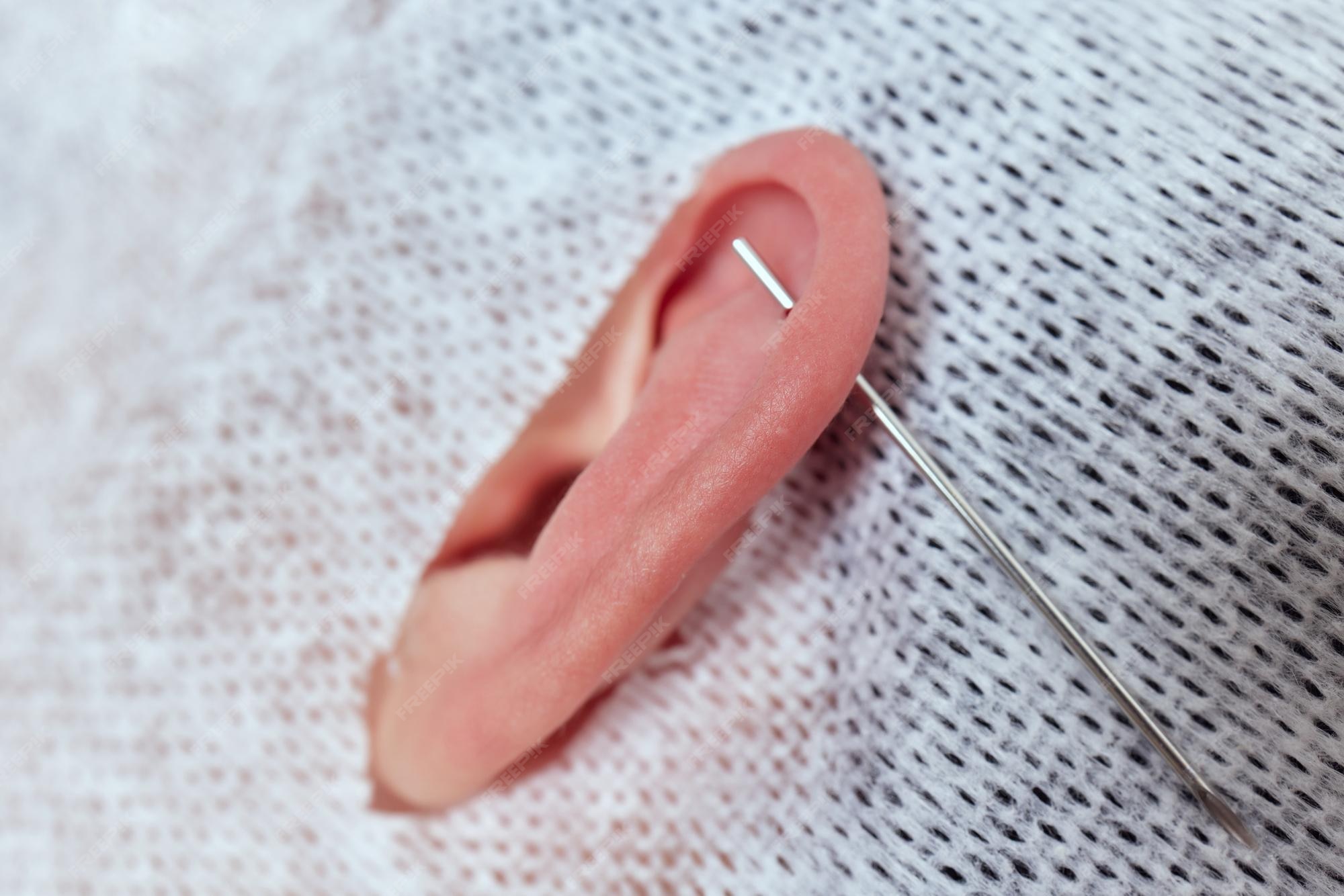 Premium Photo | Piercings on an ear conch and helix piercings close up  professional holding the jewel