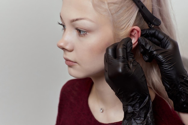 Foto piercing su un orecchio conchiglia e elica piercing da vicino professionista che tiene il gioiello