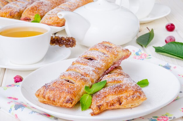 Pies from puff pastry with cherry with powdered sugar and mint