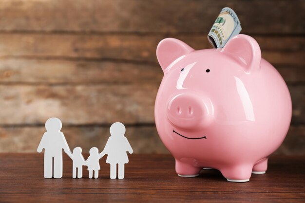 Photo pig money box and paper decor on wooden wall background