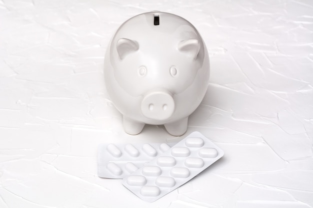 Pig piggy bank and blister of pills on a white background